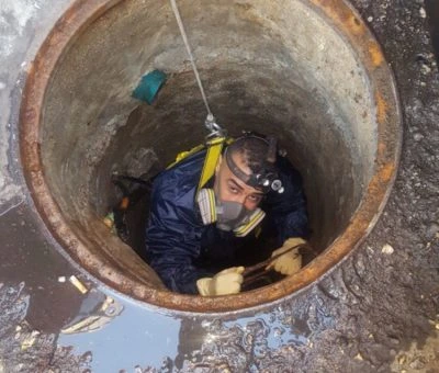 Operario de fontanería con equipo de seguridad realizando trabajos de saneamiento en un pozo en Madrid